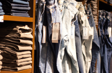 Stacked jeans and hanging denim apparel featuring smart retail tags inside a modern apparel store for automated inventory management.