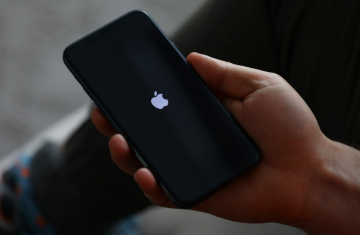 A user holding an iPhone for close-range wireless communication interaction, exploring whether a smartphone can act as an NFC tag.