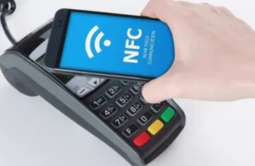 A person using a smartphone with an NFC screen display to tap on a POS payment terminal for contactless mobile transactions