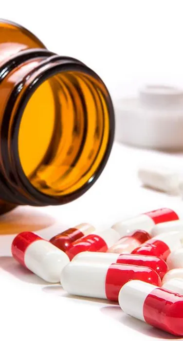 Pharmaceuticals Amber Medicine Bottle Spilling Red and White Capsules