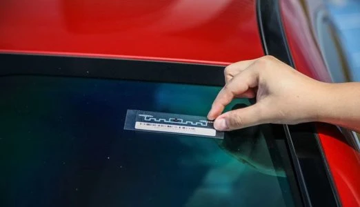 RFID Windshield Label Applying an RFID Windshield Label to a Red Car Window