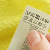 Person Holding a Textile Care Label with Washing Symbols