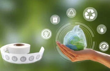 Roll of PCR PP RFID labels displayed next to a hand holding a globe surrounded by eco-friendly icons.