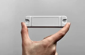 Person holding a durable, screw-mounted hard RFID tag designed for industrial asset tracking and recycling applications.