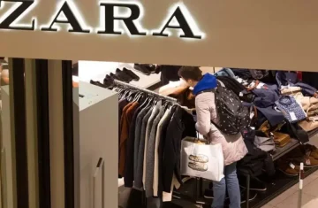 Customer shopping inside a Zara retail store browsing clothing racks under the illuminated brand logo