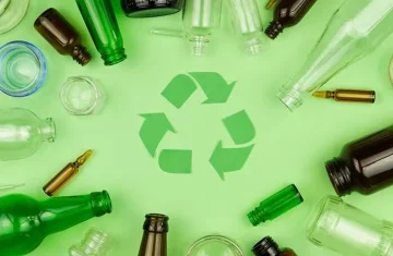 A variety of glass bottles surrounding a green recycling symbol on a green background, illustrating glass recycling