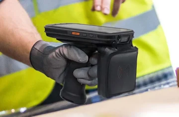 Handheld RFID Device in Use by Warehouse Worker A worker holding a handheld RFID scanning device in a warehouse or logistics setting.