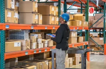 Is Your Inventory Shrinkage Costing 1M Yearly RFID s Silent Theft Solution A warehouse worker scanning packages on high shelves with a handheld device for inventory management.