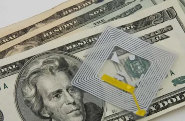 Is the Cost of RFID Tags Killing Your Budget Here s How to Fix It RFID tag placed on top of US dollar bills, highlighting the connection between technology and money.