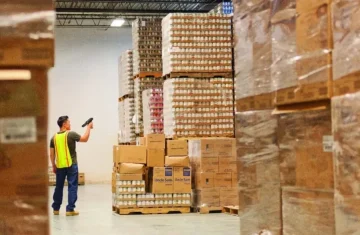 Warehouse worker using an RFID reader to check inventory. A warehouse worker scanning a pallet of boxes using an RFID handheld reader.
