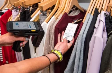 Simply RFID Strategies for Retail Success A Comprehensive Guide Person scanning RFID tag on clothing in a retail store using a handheld scanner.