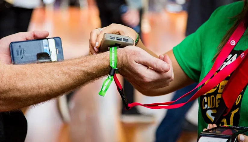 A person using an NFC-enabled wristband to make a contactless interaction at an event. T5577 Chip