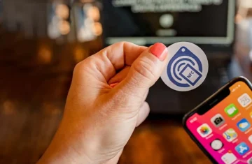 A person holding an NFC sticker near a smartphone, showcasing the NFC technology for easy connection.