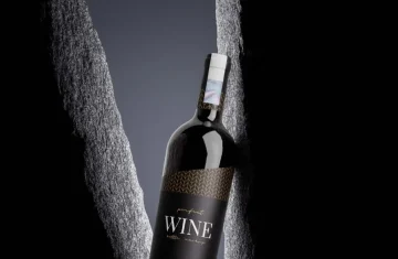 A close up shot of a wine bottle with a sleek, elegant design and a textured black background.