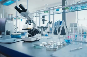 A microscope and laboratory equipment on a desk in a modern science lab.
