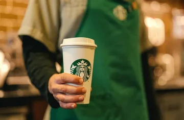 A Starbucks employee holding a cup of coffee.
