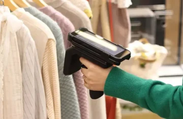 Warehouse worker using an RFID scanning device A worker using an RFID scanning device to scan clothing tags on a store shelf.