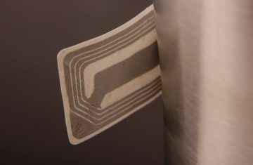 Close-up of an RFID sticker on a metallic surface showing intricate coil design.