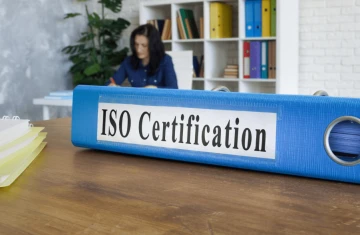 ISO Certification Binder on Office Desk A blue ISO certification binder placed on a desk with office background.