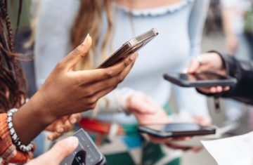 People holding their iPhones close together to use the NameDrop feature for contactless contact sharing.