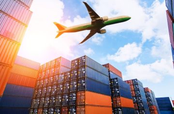 Airplane Flying Over Containers An airplane flying above a stack of colorful shipping containers in a logistics yard