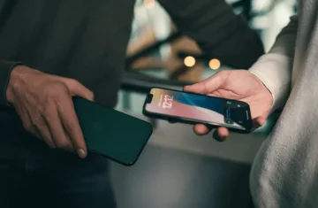 NFC Data Exchange Between Two Smartphones Two people holding smartphones close together, possibly exchanging information via NFC technology.