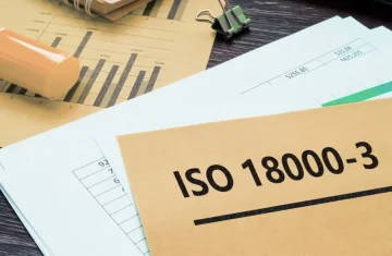 ISO 18000-3 Standard Documentation A folder labeled "ISO 18000-3" on a desk with financial charts and office supplies.