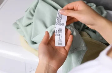RFID Care Labels: Enhancing Brand Interaction and Customer Experience A person's hands hold up the care label of a light green garment, clearly showing the embedded RFID tag and care instructions.