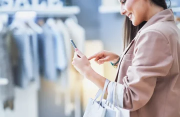 The Definitive Guide to the Website NFC Tag Seamless Digital Connection and Commercial Advantage A woman shopping in a retail store, interacting with her smartphone while holding shopping bags.