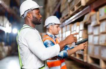 The Future is Tagged Unlocking Unprecedented Transparency with RFID in Smart Packaging Two warehouse workers scanning inventory with handheld devices in a large storage facility.