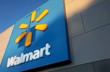 Close-up of a Walmart storefront sign with the yellow spark logo and white “Walmart” lettering on a blue panel.