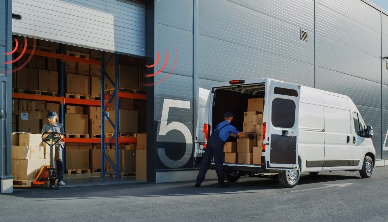 Worker with a hand truck (left) loads boxes into a van (right) at a warehouse dock, with RFID signal icons.