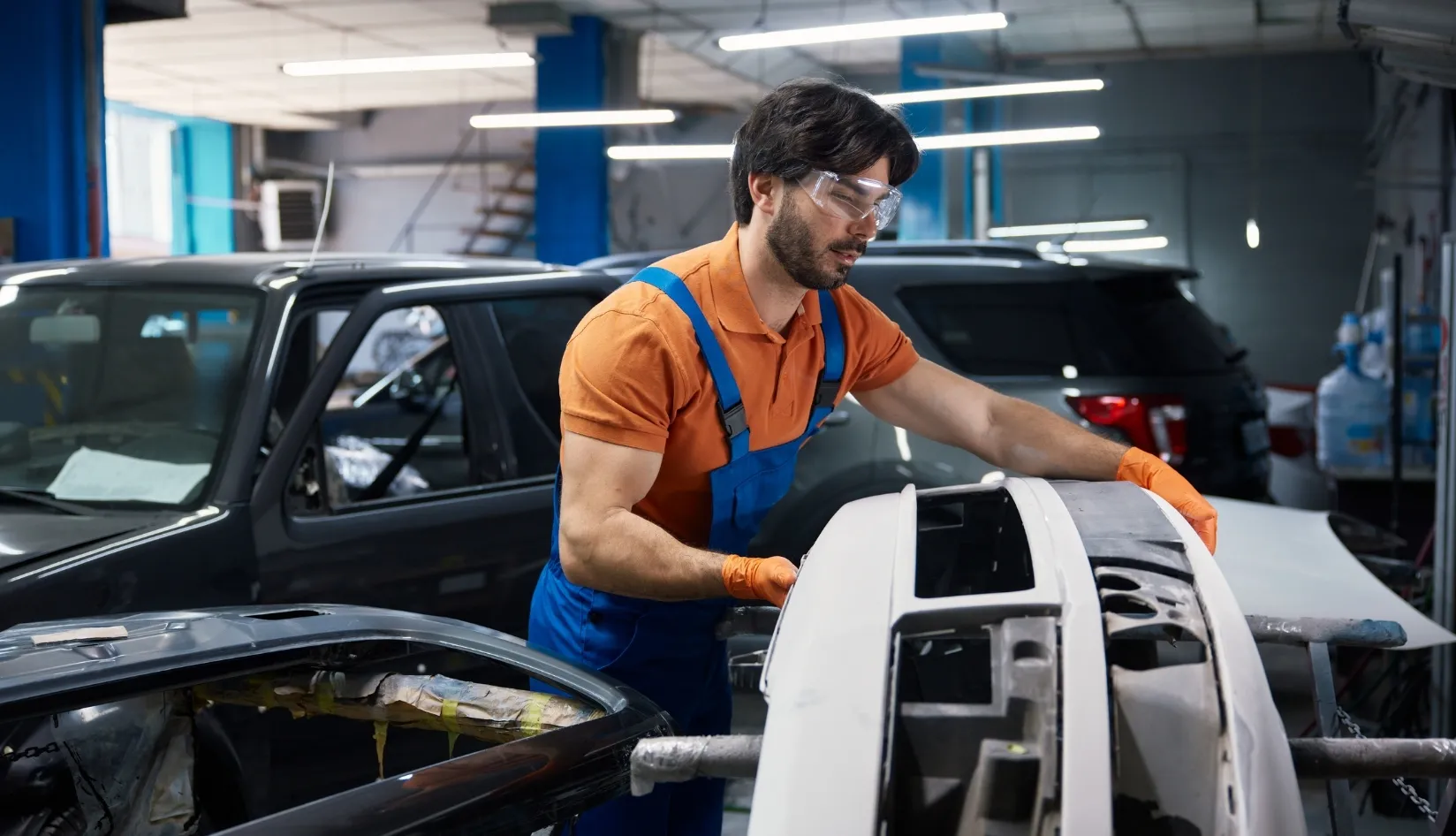 Auto Body Repair Workshop Worker in an auto body shop handling a car bumper
