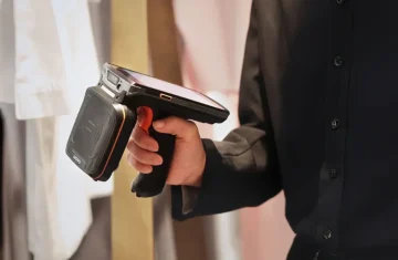 Hand holding a rugged handheld RFID scanner in a retail store