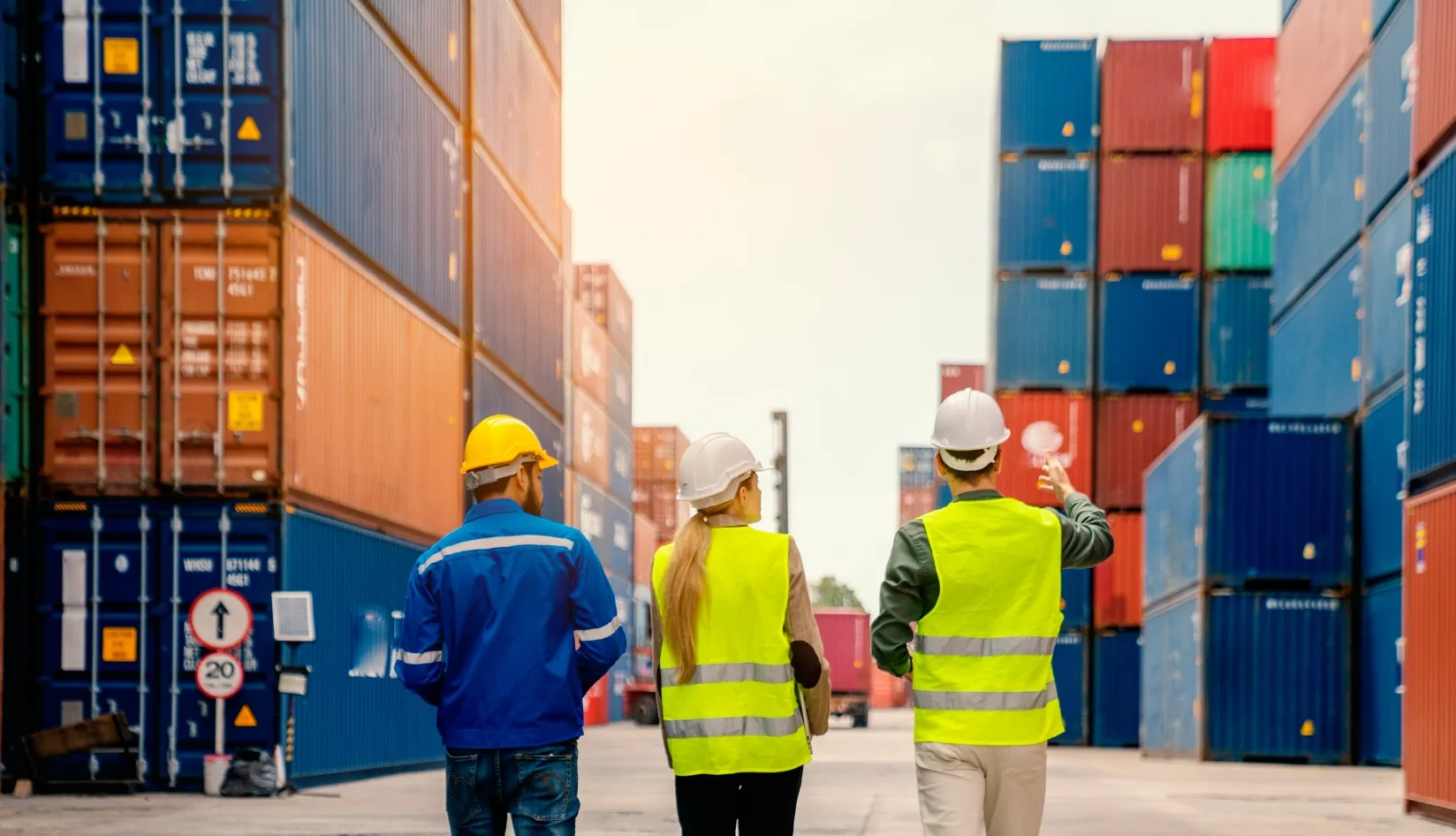 Port Workers Managing Shipping Containers Three workers (in hard hats/vests) inspect stacked shipping containers at a port.