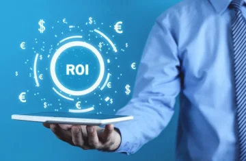Businessperson holding a tablet with a glowing “ROI” graphic and floating currency symbols on a blue background.