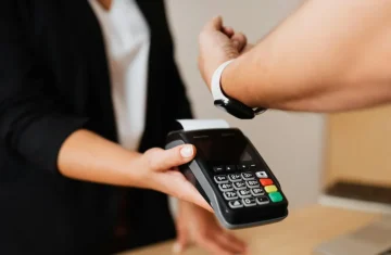 Contactless Payment with a Smartwatch A customer wearing a smartwatch holds their wrist near a handheld card terminal for a contactless payment.