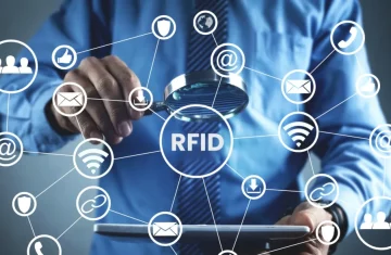 Do You Really Need RFID User Memory or Is a Standard EPC Tag Enough Business professional holds a magnifying glass over RFID text with connected icons for data security wifi and communication.