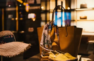 Luxury handbag display in boutique window with yellow leather tote floral scarf and yellow shoes.