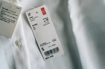 Uniqlo RFID clothing tag attached to white shirt showing barcode size S and price 1990 yen