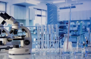 Modern laboratory scene with microscope glass test tubes and flasks on a clean bench in a bright research lab.