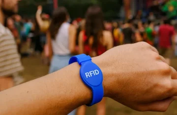 Blue RFID wristband on a wrist at a crowded outdoor festival