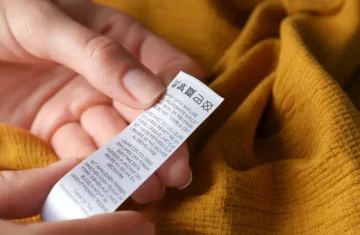 How to Choose RFID Care Labels Based on Garment Type Hands holding a garment care label attached to yellow fabric, showing washing instructions and textile details.