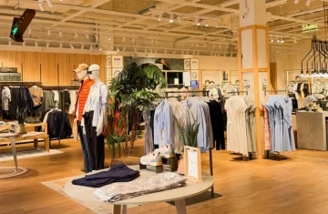 Modern fashion retail store with clothing displays and mannequins, representing NFC smart apparel, digital product passports, authenticity verification, transparency, and circular fashion.