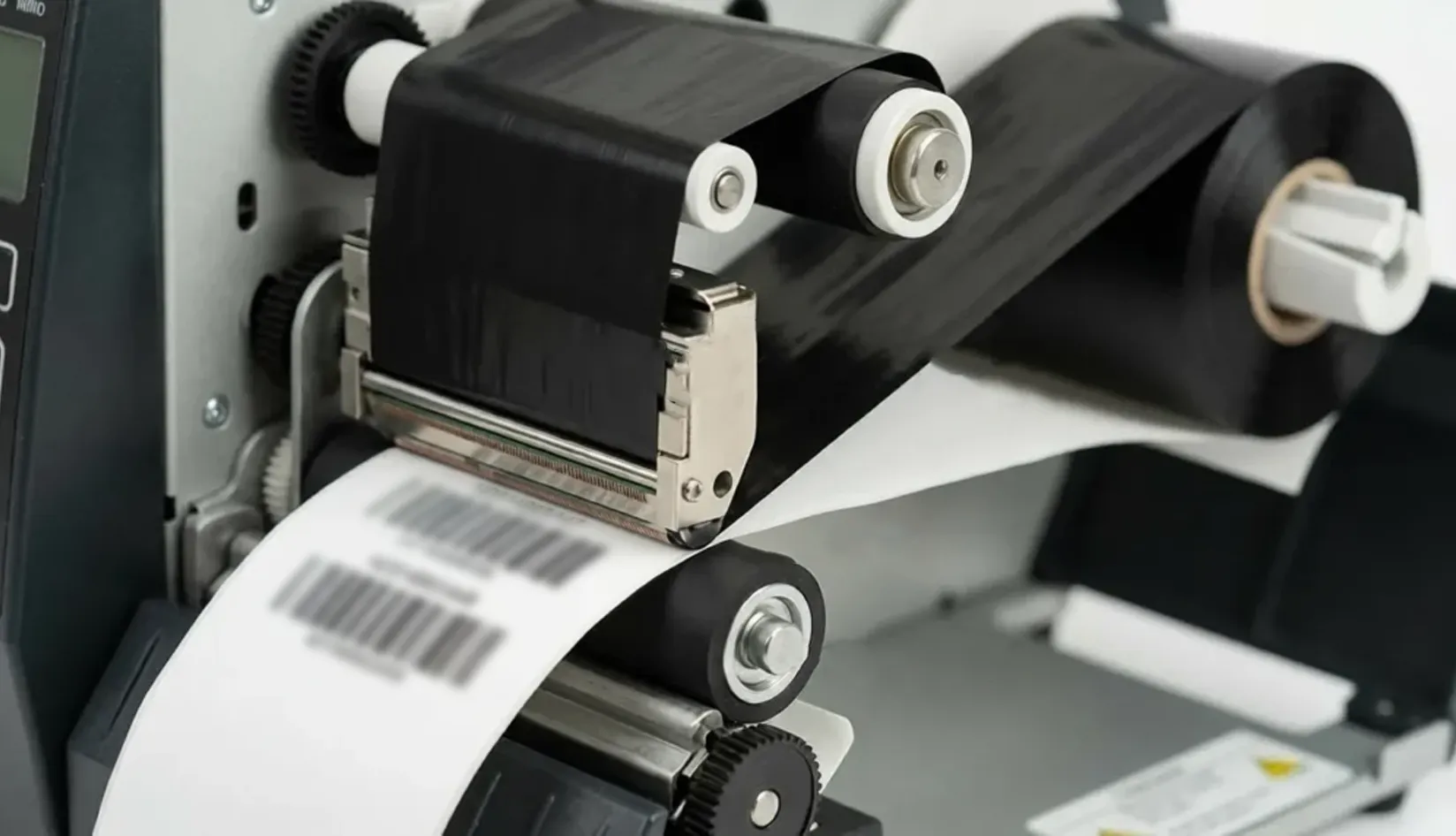 Black thermal transfer ribbon printing barcode labels in an RFID label printer, showing ribbon width, print clarity, and durable label identification.