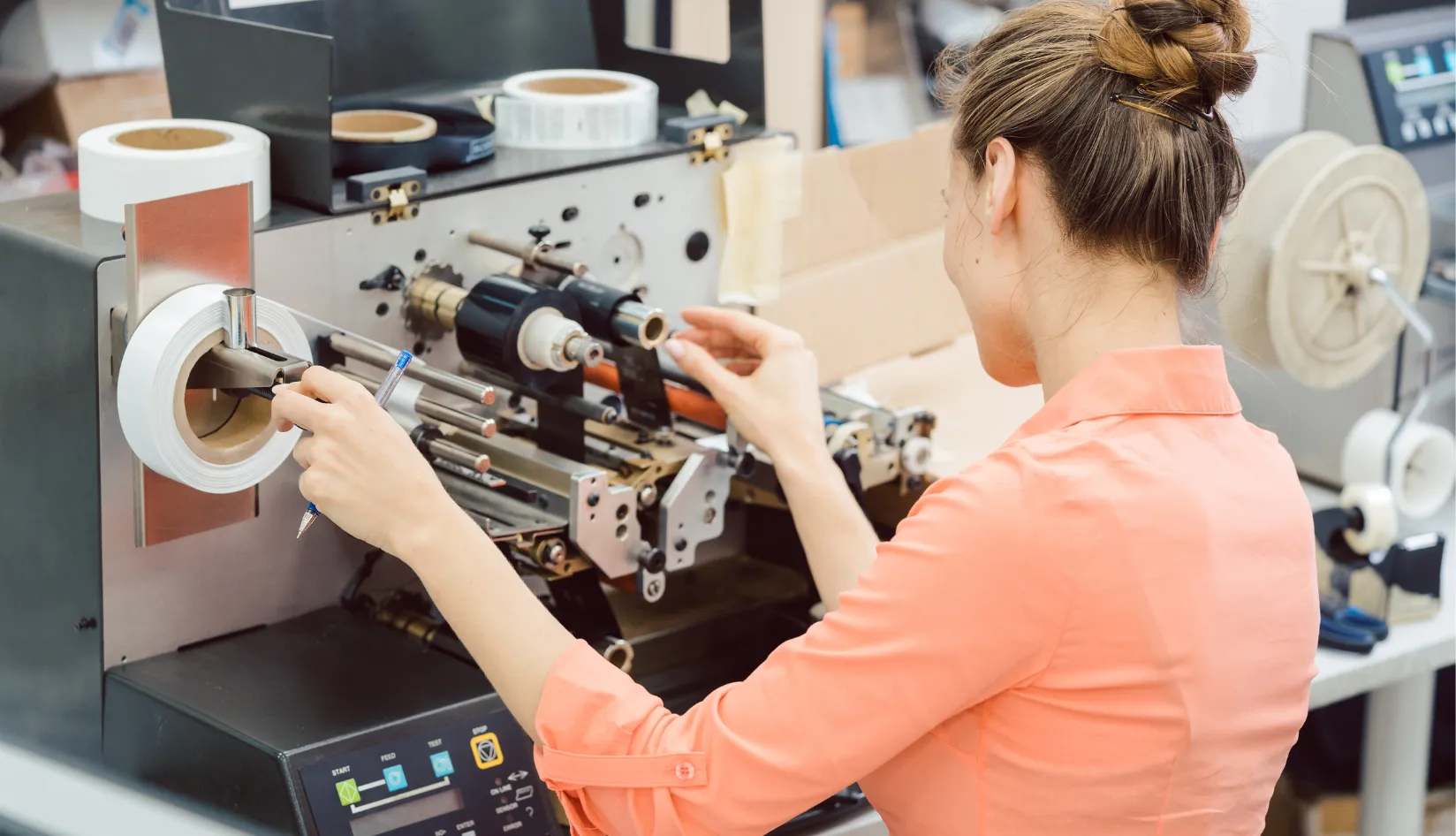 RFID Printing Direct Thermal vs Thermal Transfer for RFID Labels Technician adjusting a roll of RFID labels on industrial label converting equipment during production setup.