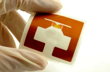 UHF RFID Chip Antenna Matching What Changes When You Switch Chips Gloved hands holding a UHF RFID inlay with chip and antenna, showing chip antenna matching for stable label performance.